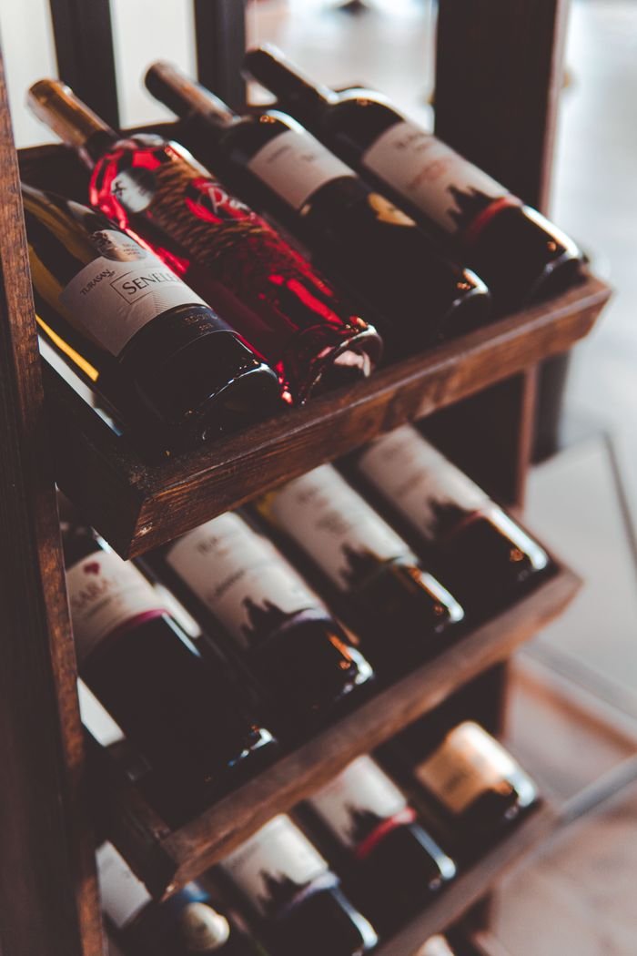 Elegant wooden wine rack filled with assorted red and white wine bottles on display indoors.